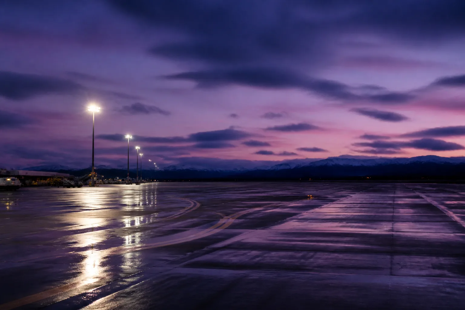 Twilight runway at a Scottish airport, soft purple sky and bright apron lights.